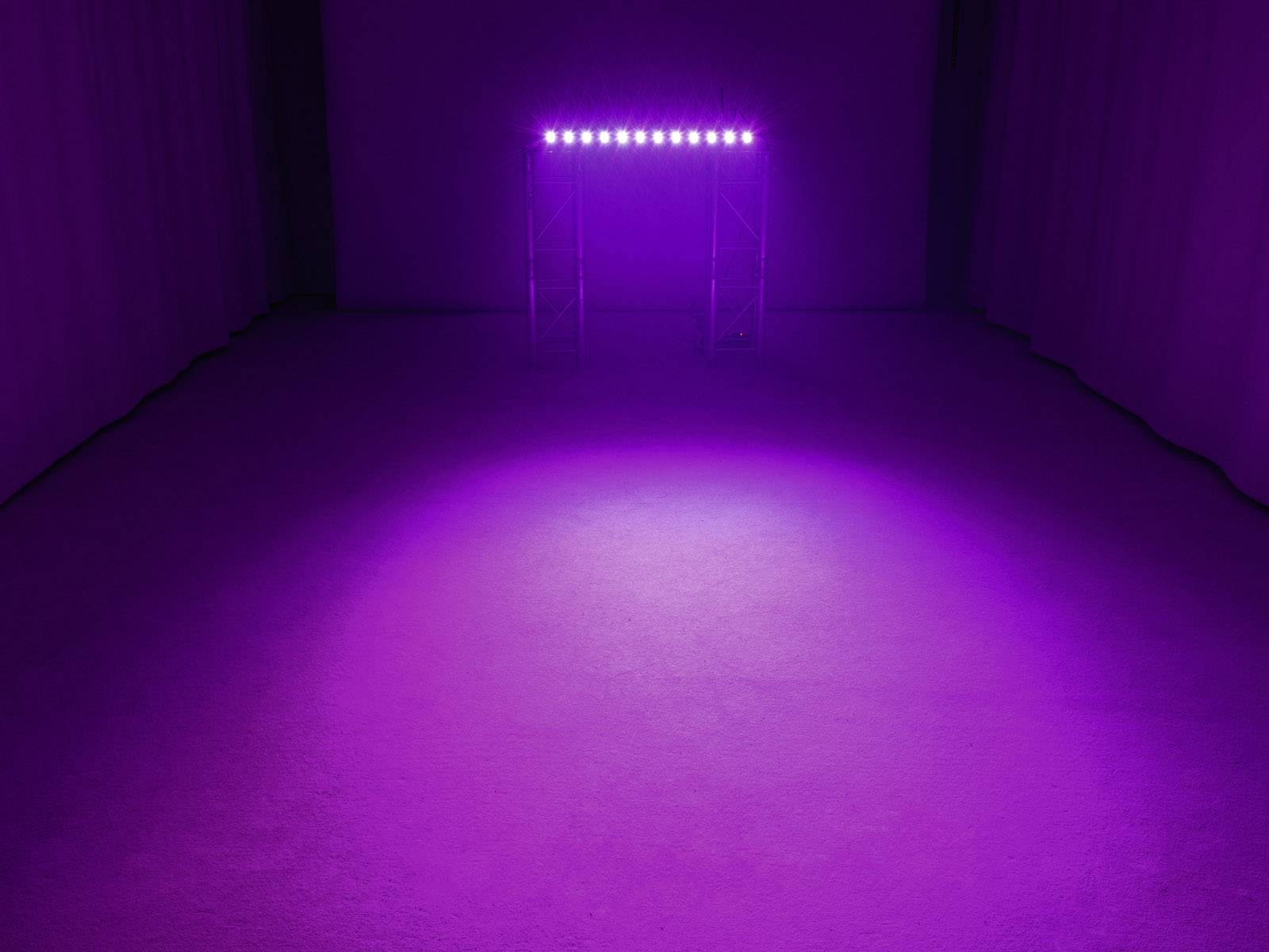 Prázdný prostor s fialovým osvětlením pocházejícím z řady reflektorů na stropě vytváří mystickou atmosféru.