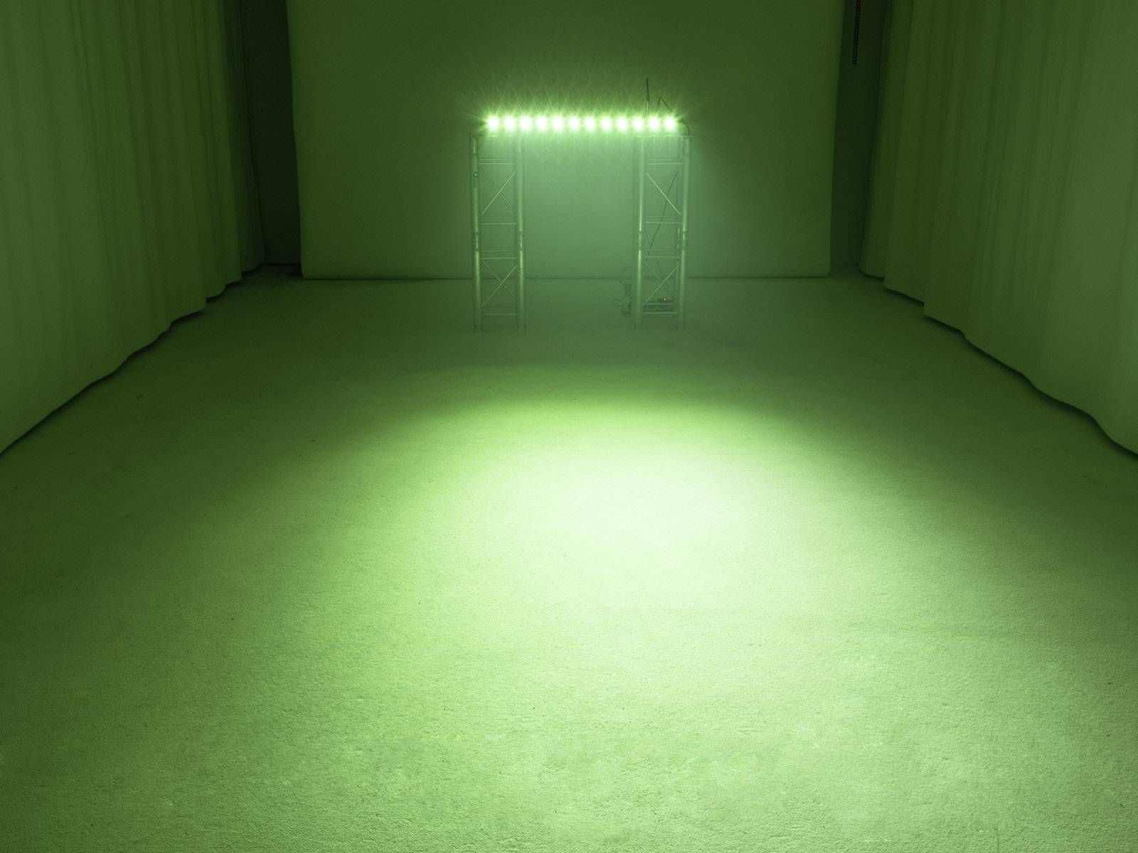 Místnost s nazelenalým osvětlením vycházejícím z konstrukce s několika LED světly osvětluje plochu na podlaze.