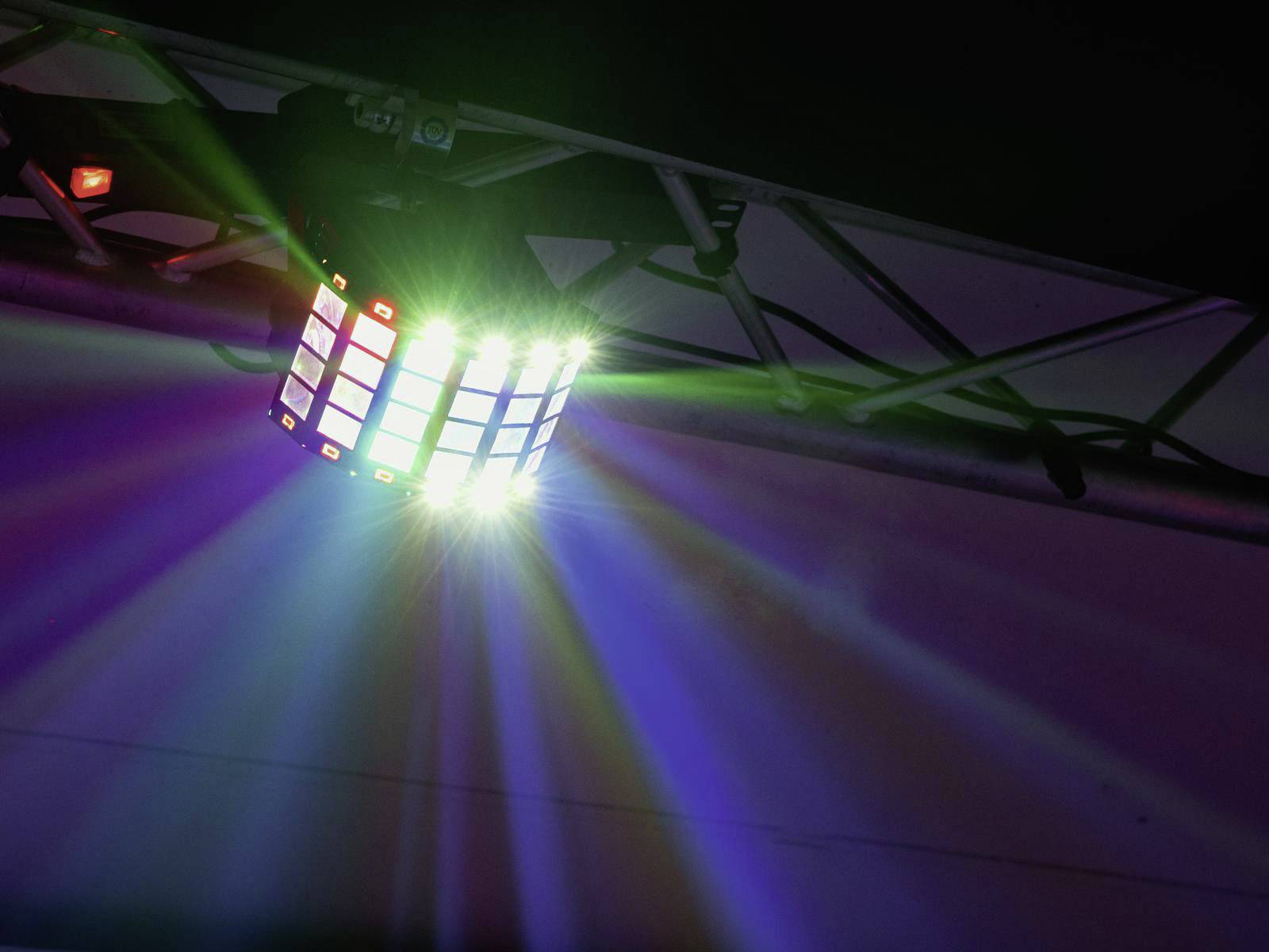 Vícebarevná LED lampa visí z traverzy a vyzařuje pestré světelné paprsky, které osvětlují prostor.