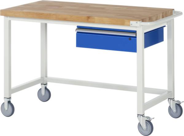 Pracovní stůl s dřevěnou deskou, bílým kovovým rámem, modrou zásuvkou a čtyřmi kolečky. Ideální do dílen nebo tvůrčích prostor.