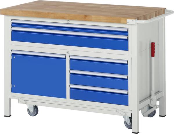 Bílý pracovní stůl se čtyřmi modrými zásuvkami a modrými dvířky, nahoře s dřevěnou deskou. Stůl stojí na čtyřech kolečkách, která umožňují snadné přemísťování.