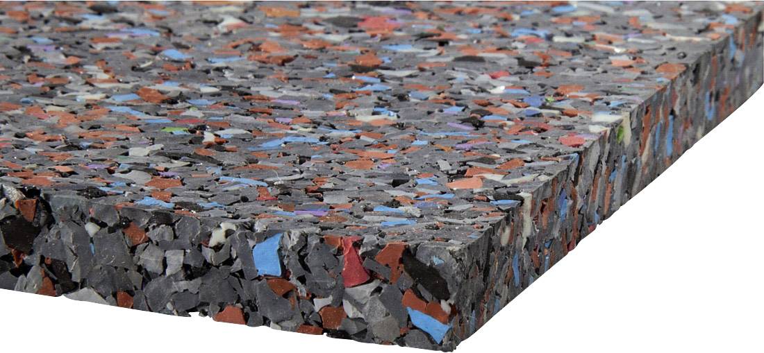 Podložka z rozdrcené, vícebarevné pěnové hmoty, převážně v černé, červené a modré barvě, ukazuje design z recyklovaného materiálu.