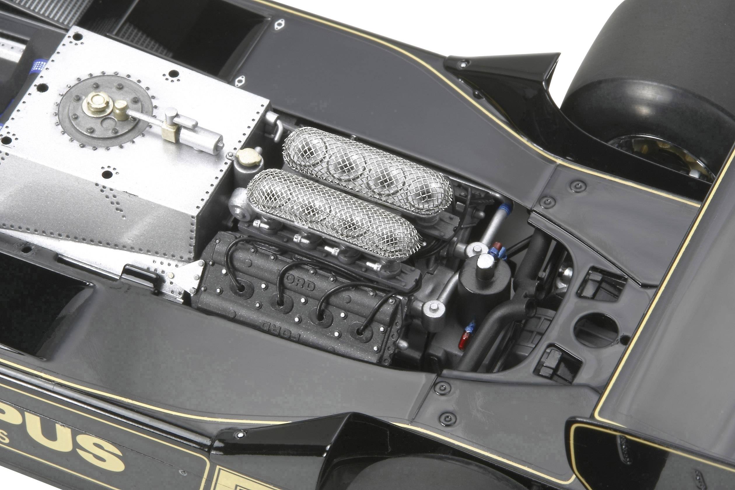 Detailní záběr motoru formule 1 v černém závodním voze se zlatými akcenty, odhalující strukturu motoru a jeho komponenty.
