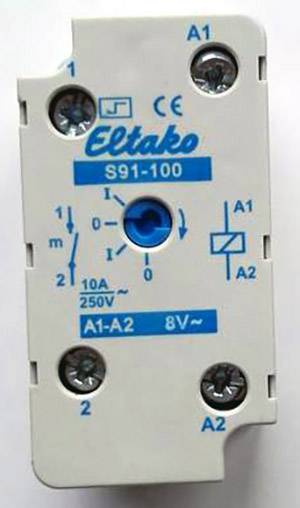 Elektronické relé s modrým nápisem 'Eltako S91-100', na obrázku jsou znázorněny připojovací body a spínací symboly.