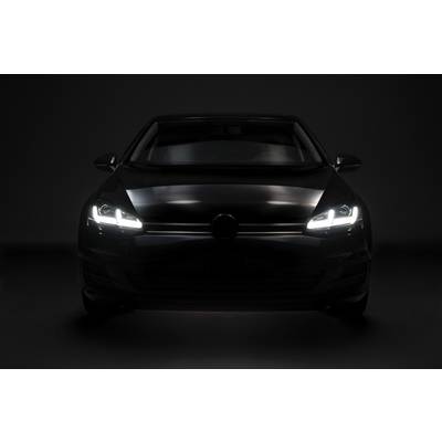 Černé auto se zapnutými světly stojí čelně v tmavém prostředí.