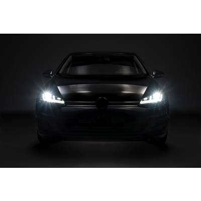 Automobil s rozsvícenými tlumenými světly pohledem zepředu v tmavém prostředí.