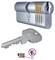 Pohled na řez zámkovým cylindrem BASI ukazuje vnitřní kolíčky. Níže je zobrazen odpovídající klíč. Červený kruh s čárou přes 'Bohrschutz' označuje ochranu proti vrtu.