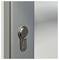 'Stříbrný kovový zámkový válec na šedých dveřích s kulatou klíčenkou a logem značky'