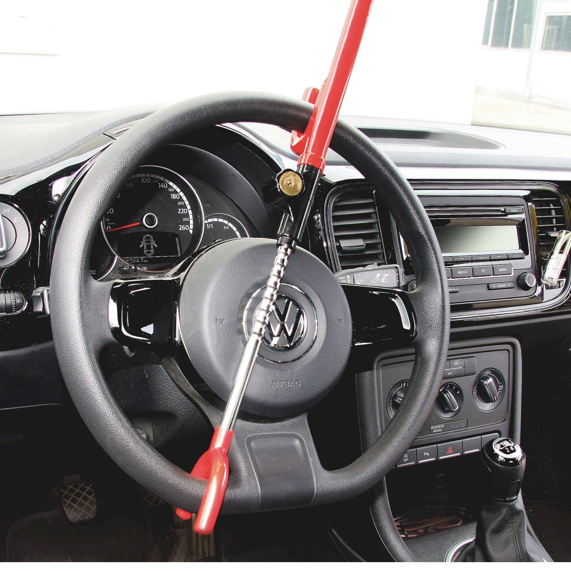 Vnitřek automobilu s bezpečnostní pákou: Červená zábrana proti krádeži je připevněna na volantu a brání řízení vozidla.