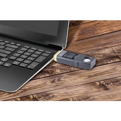 Notebook s USB připojeným snímačem otisků prstů na dřevěném stole.