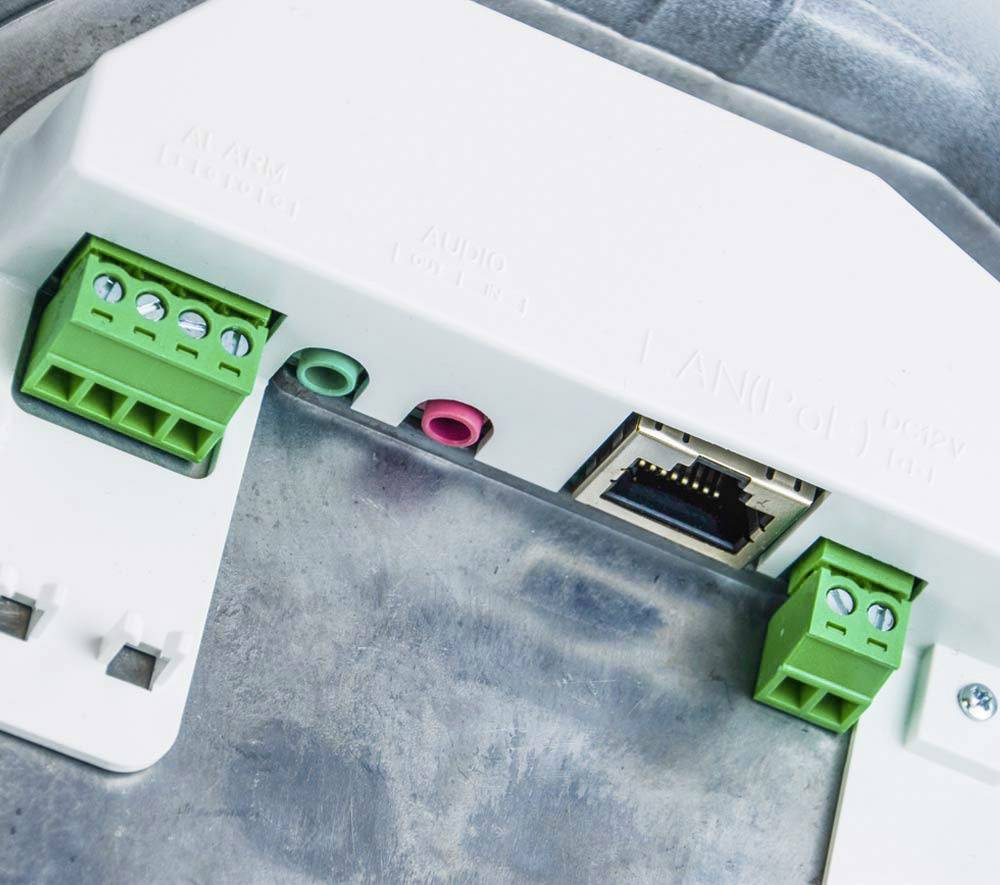 Síťový konektor a zelené svorkovnice na elektronickém zařízení, pravděpodobně určené pro připojení kabelů a přenos dat.