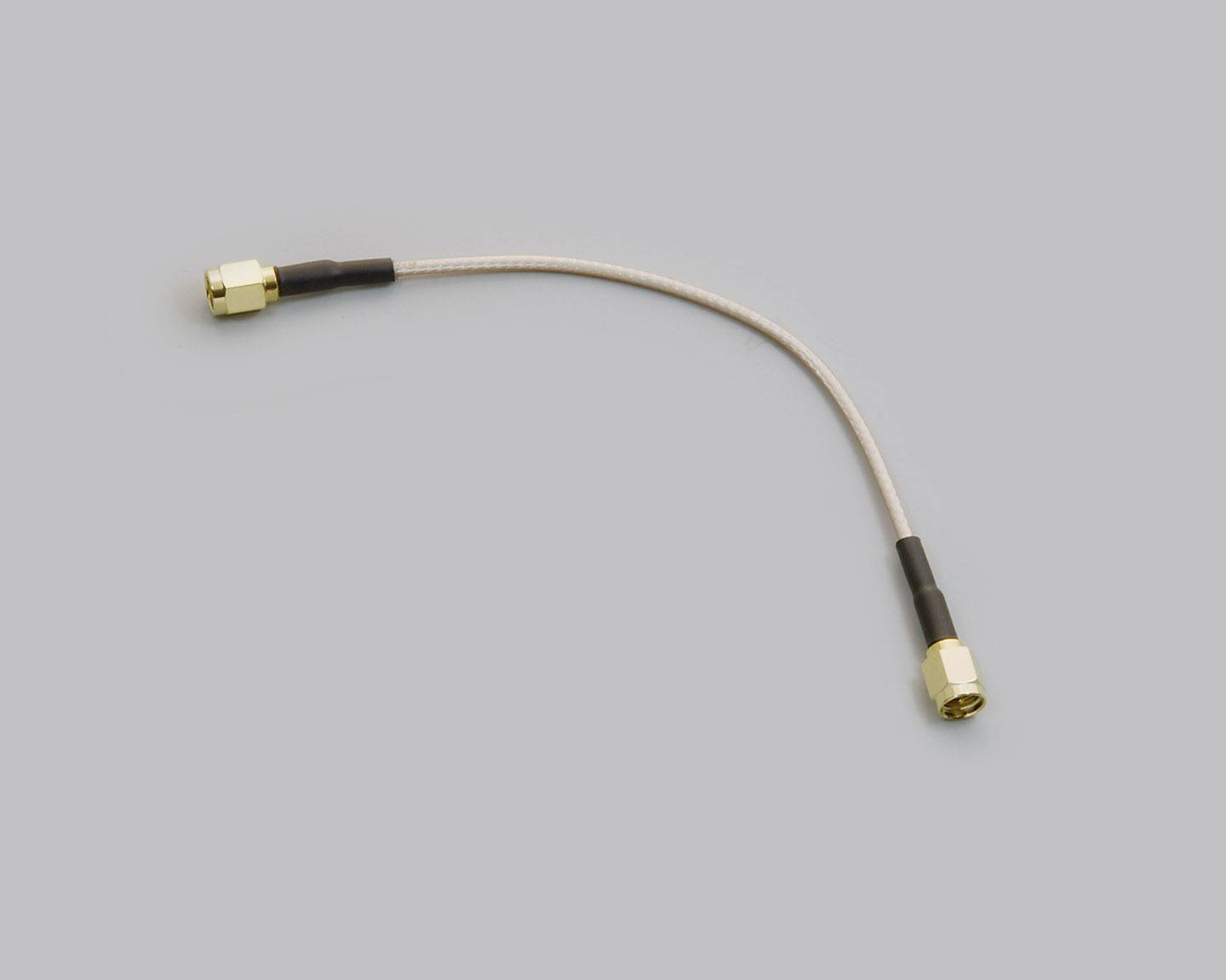 Krátký, flexibilní koaxiální kabel se zlatými konektory na obou koncích, používaný pro propojení elektronických komponent.