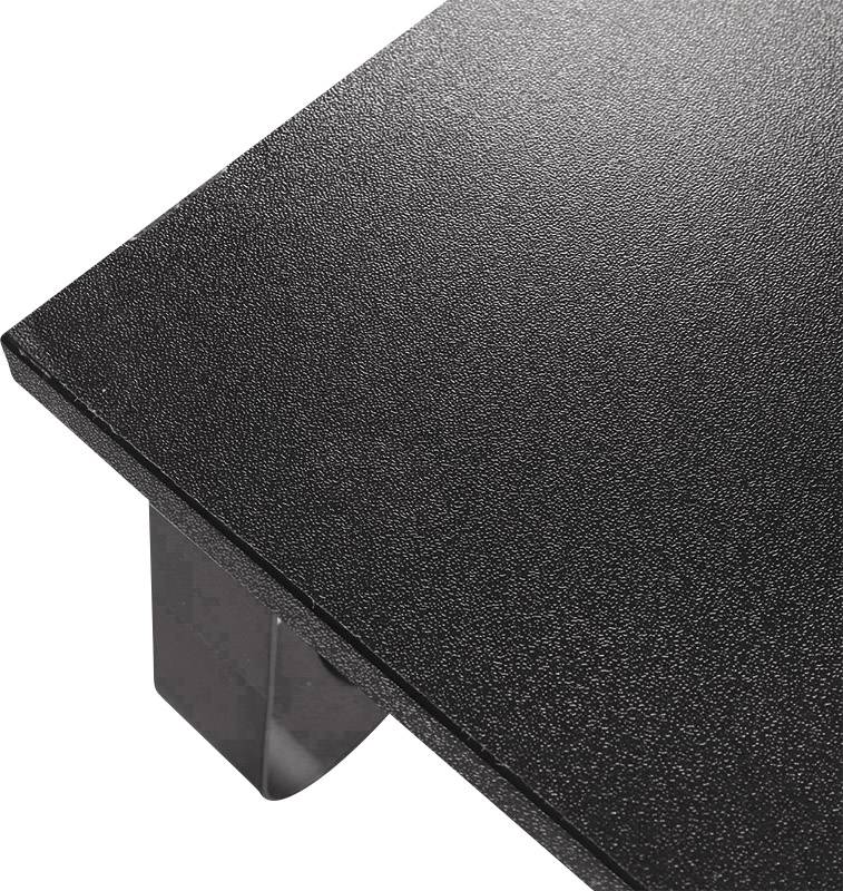 Černý stůl se strukturovaným povrchem a kovovými nohami, fotografovaný z nadhledu v rohu místnosti.