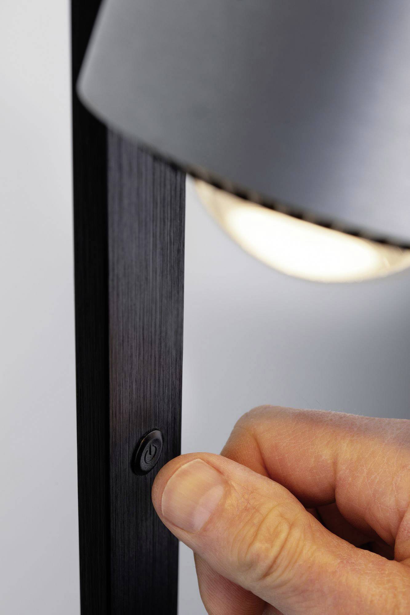 Ruka zapíná lampu stisknutím kulatého tlačítka umístěného na straně lampy.