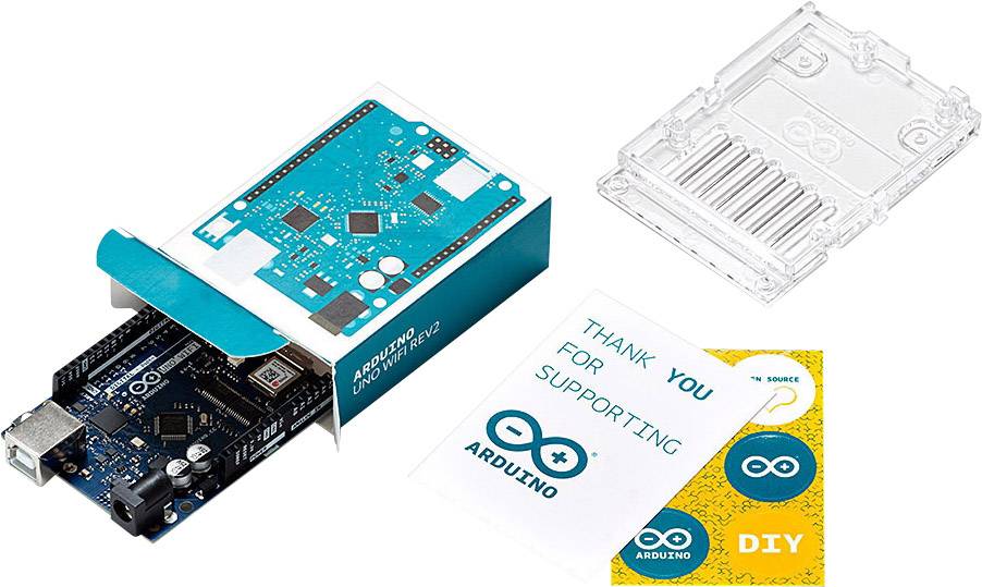 Arduino deska viditelná v otevřené krabici, vedle průhledný plastový obal a dvě kartičky s nápisy 'Děkujeme za podporu Arduino' a 'DIY'.