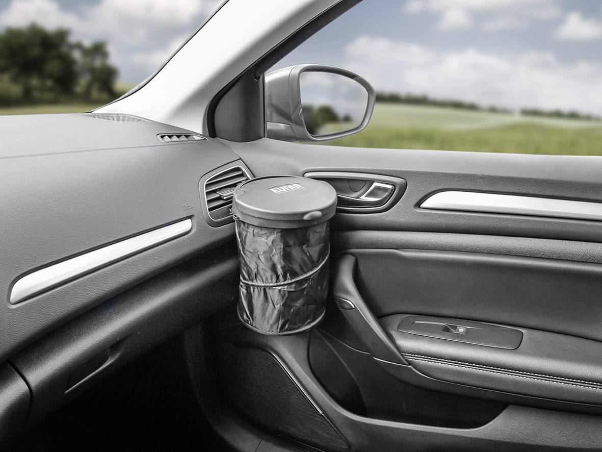 Vnitřek automobilu s malou válcovitou černou odpadkovou nádobou připevněnou u dveří spolujezdce.