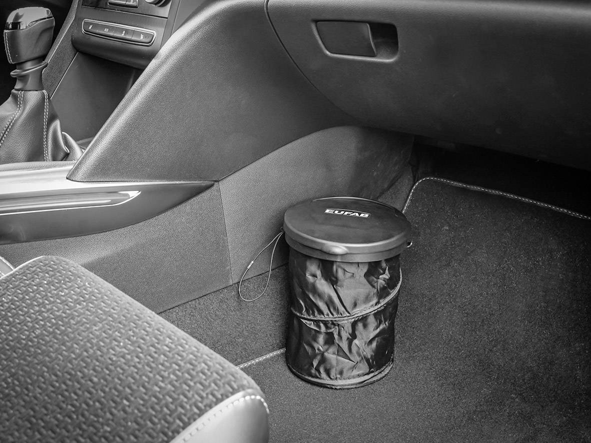 Odpadkový koš s víkem umístěný na podlaze automobilu, vhodně vsazený pod přístrojovou desku, vedle sedadla spolujezdce.