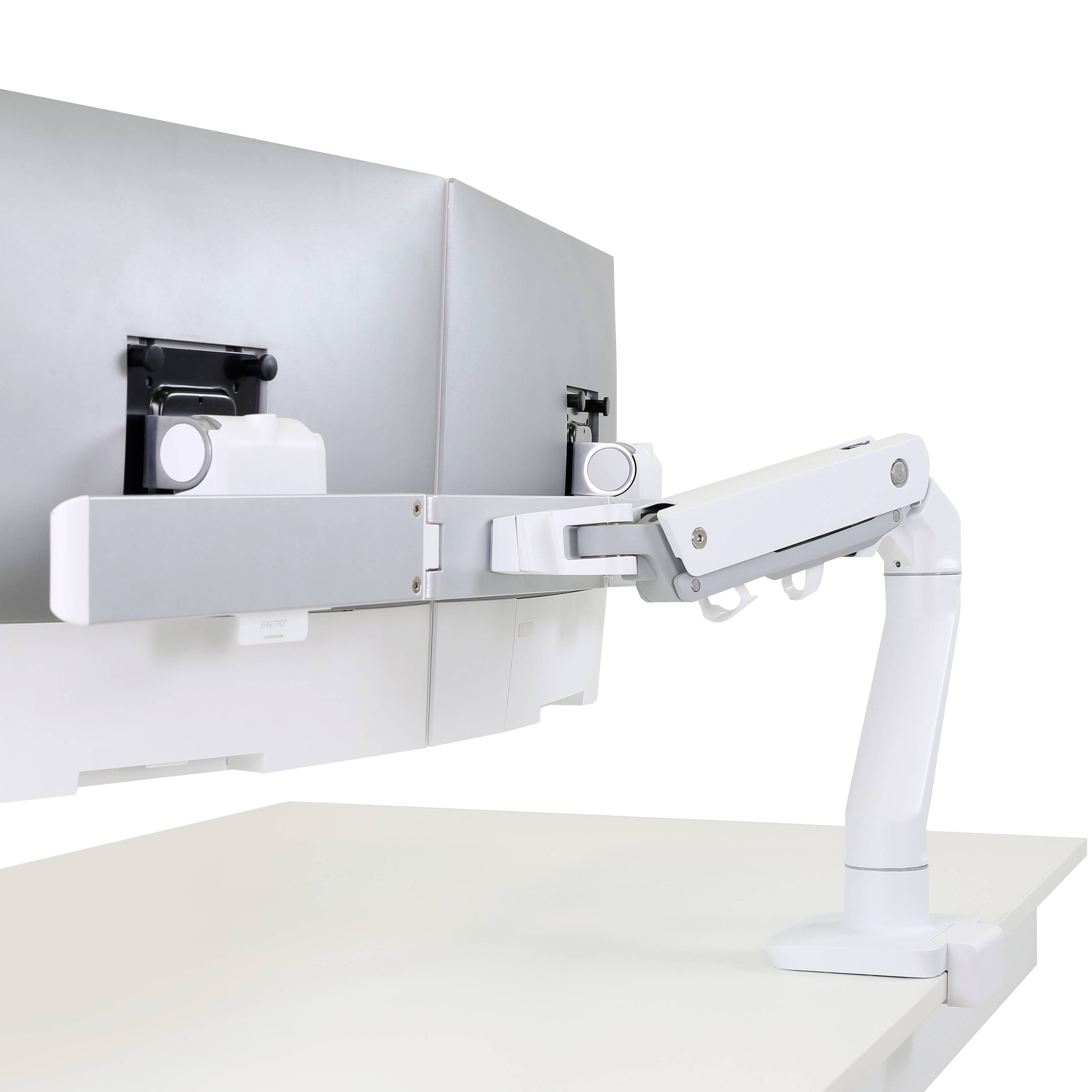 Bílé nastavitelné rameno monitoru je upevněno na monitor stojící na stole. Rameno umožňuje flexibilní nastavení polohy obrazovky.