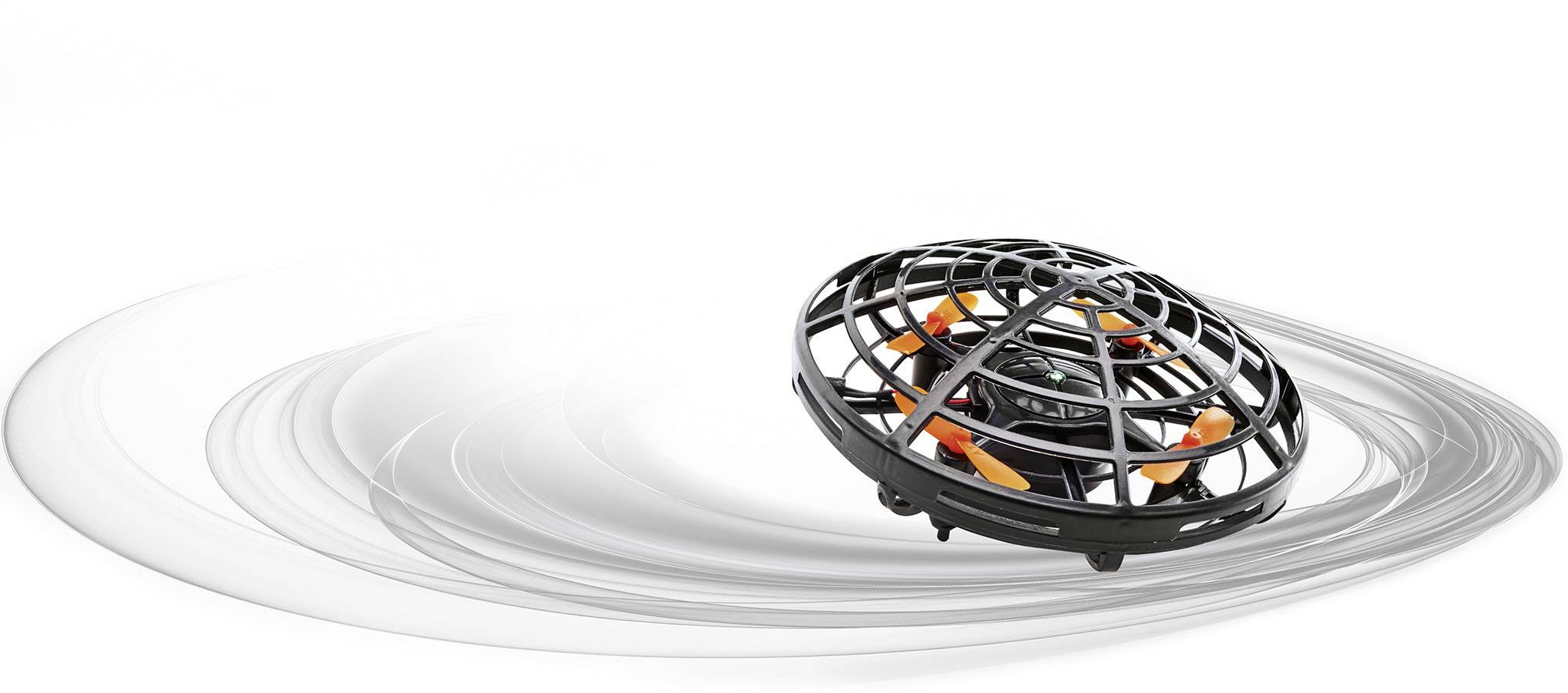 Černý dron s oranžovými vrtulemi, obklopený ochranným krytem, vznáší se nad vířivým šedým pozadím.