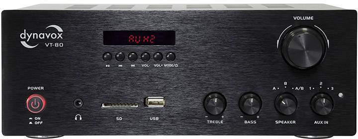 Černý zesilovač s regulátorem hlasitosti, vstupním displejem 'Aux 1', ovládáním výkonu a ekvalizéru pro basy, reproduktory a auxiliární vstup.