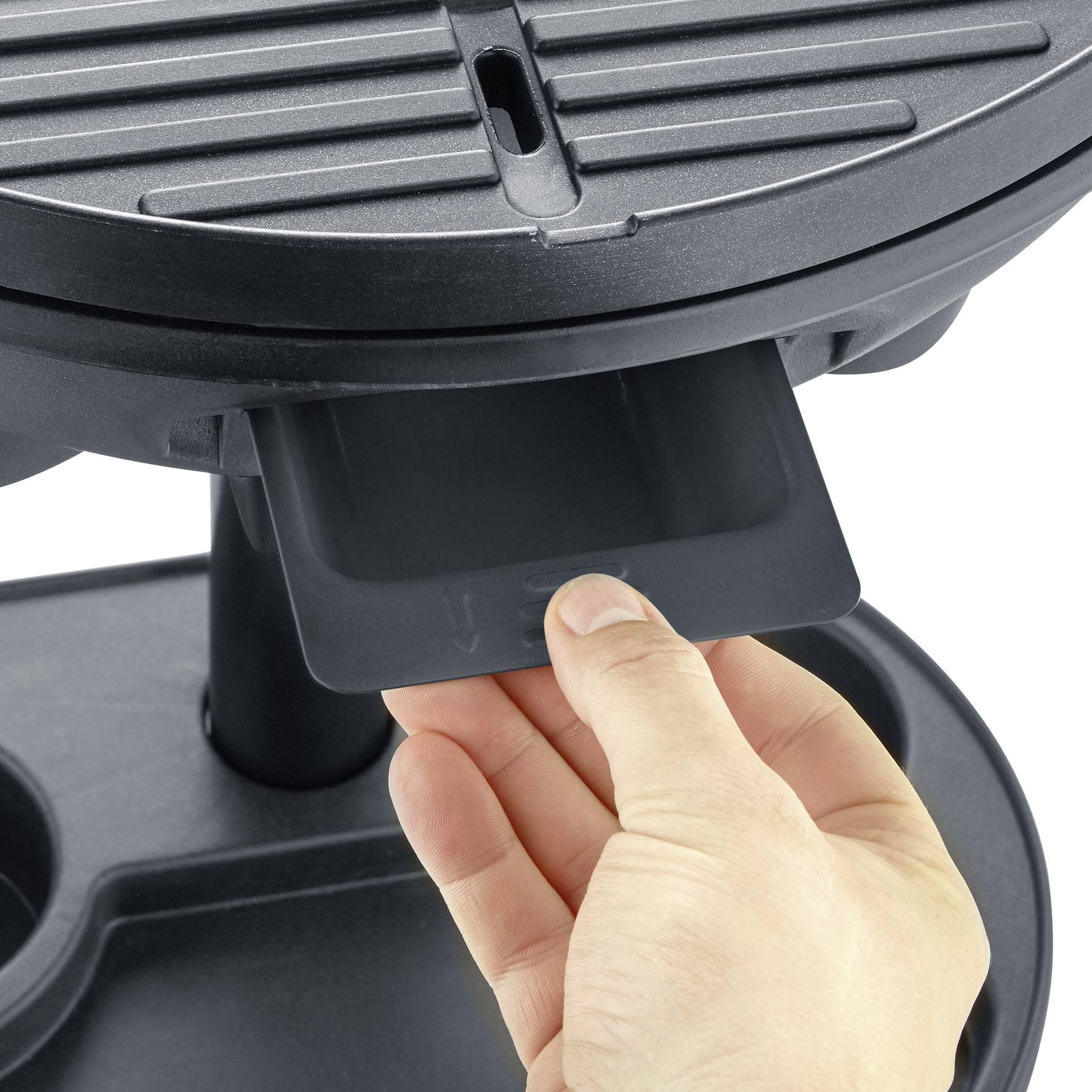 Jedna ruka otevírá spodní zásuvku elektrického grilu, která pravděpodobně slouží k zachytávání odkapávajícího oleje.