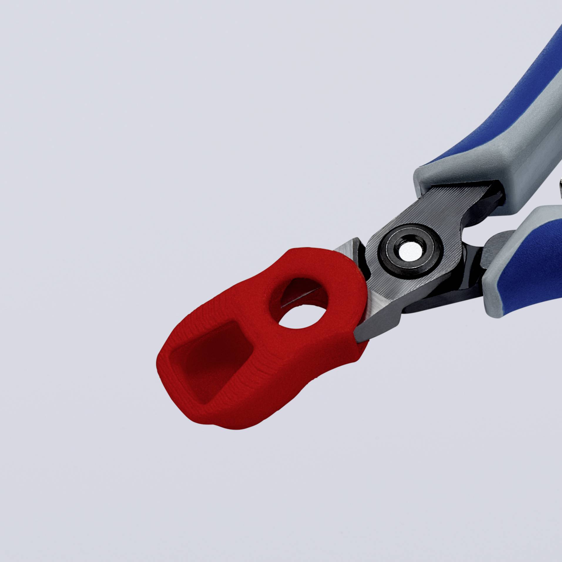 Červená svorka připevněná k šedé rukojeti před šedým pozadím.