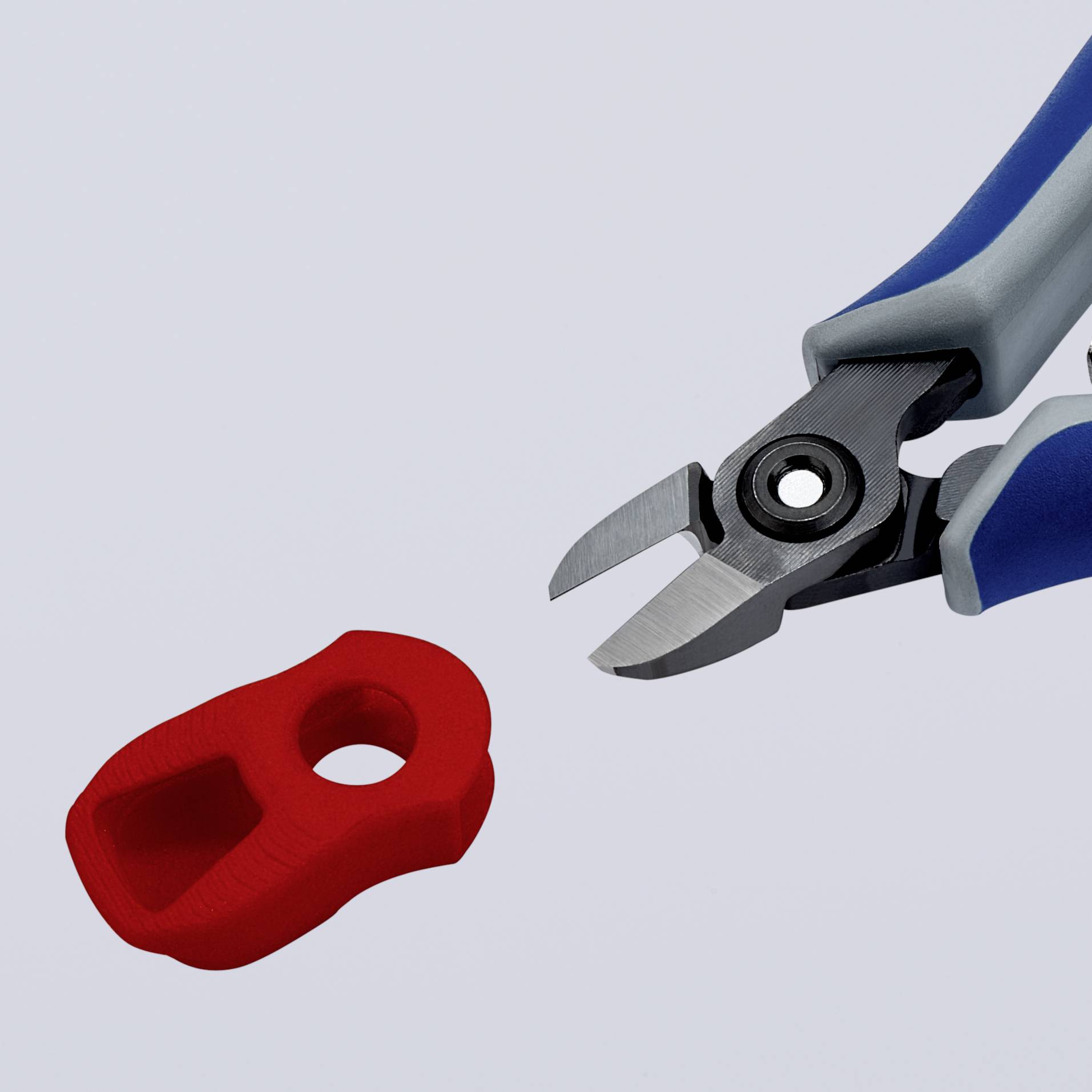 Kovové kleště stříhají malou červenou plastovou součástku.