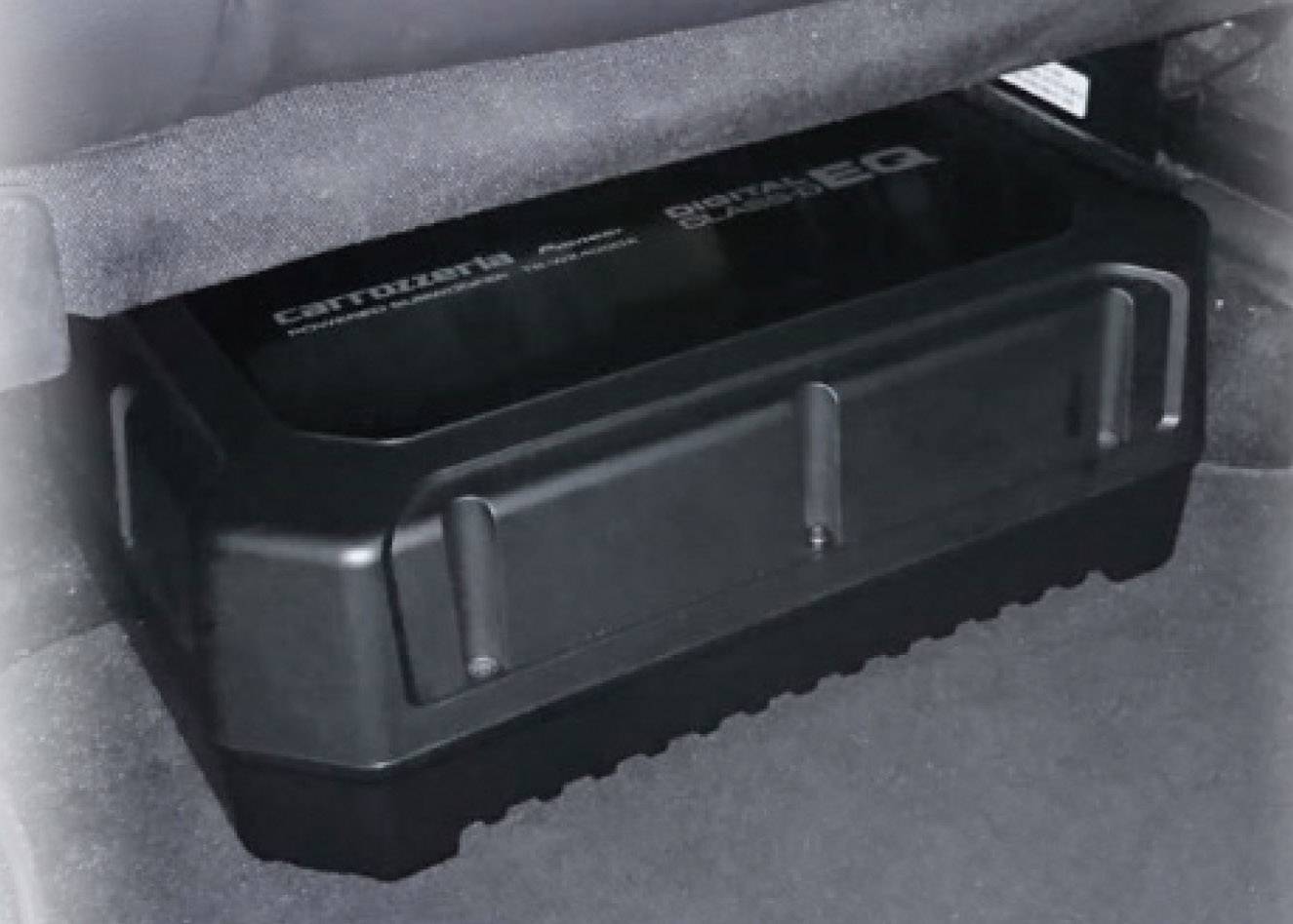 Černý zesilovač s nápisem 'Digital Power EQ' namontovaný pod sedadlem automobilu. Zesilovač je pravoúhlý a kompaktní.