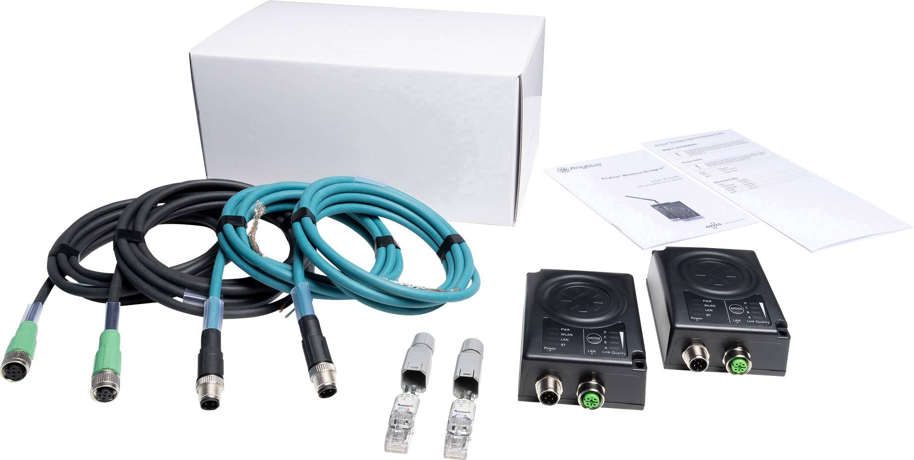 Sada elektronických zařízení se dvěma černými moduly, kabely a konektory, s návodem k obsluze v pozadí.