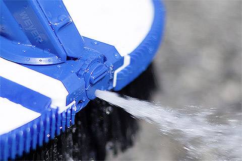 Detailní záběr modré trysky vysokotlakého čističe, která směřuje silný proud vody na čištěný povrch.