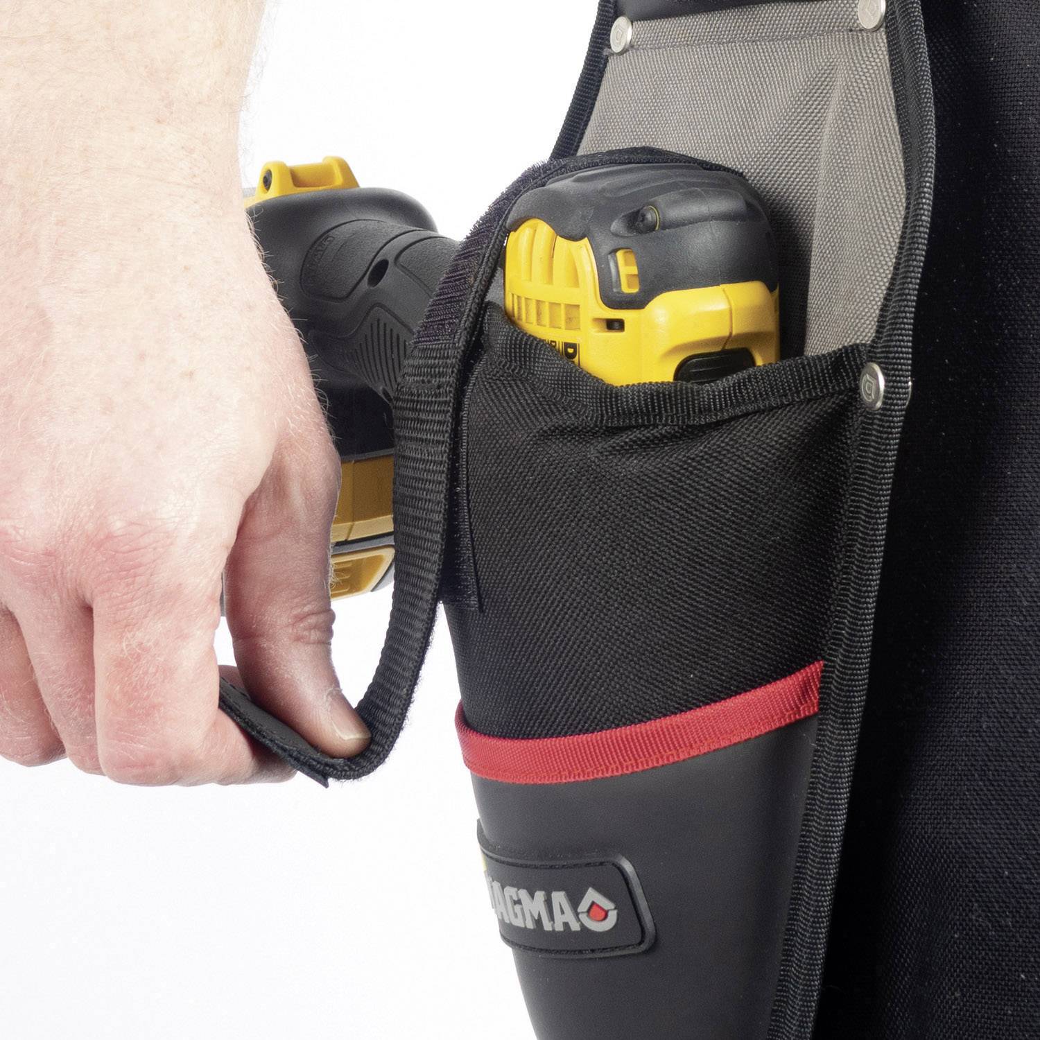 Osoba drží elektrický nástroj, který je uložen v černé a červené tašce s nápisem 'Magma'.