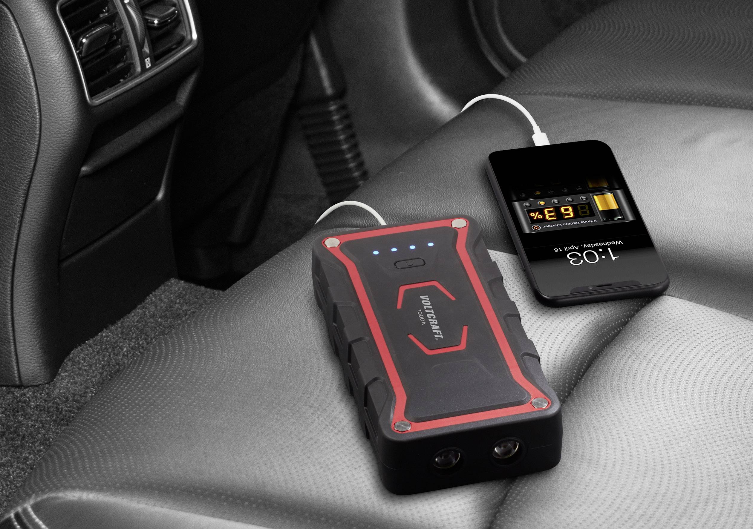 Přenosná powerbanka leží na sedadle automobilu a nabíjí smartphone pomocí USB kabelu. Na displeji telefonu jsou zobrazeny informace o nabíjení.