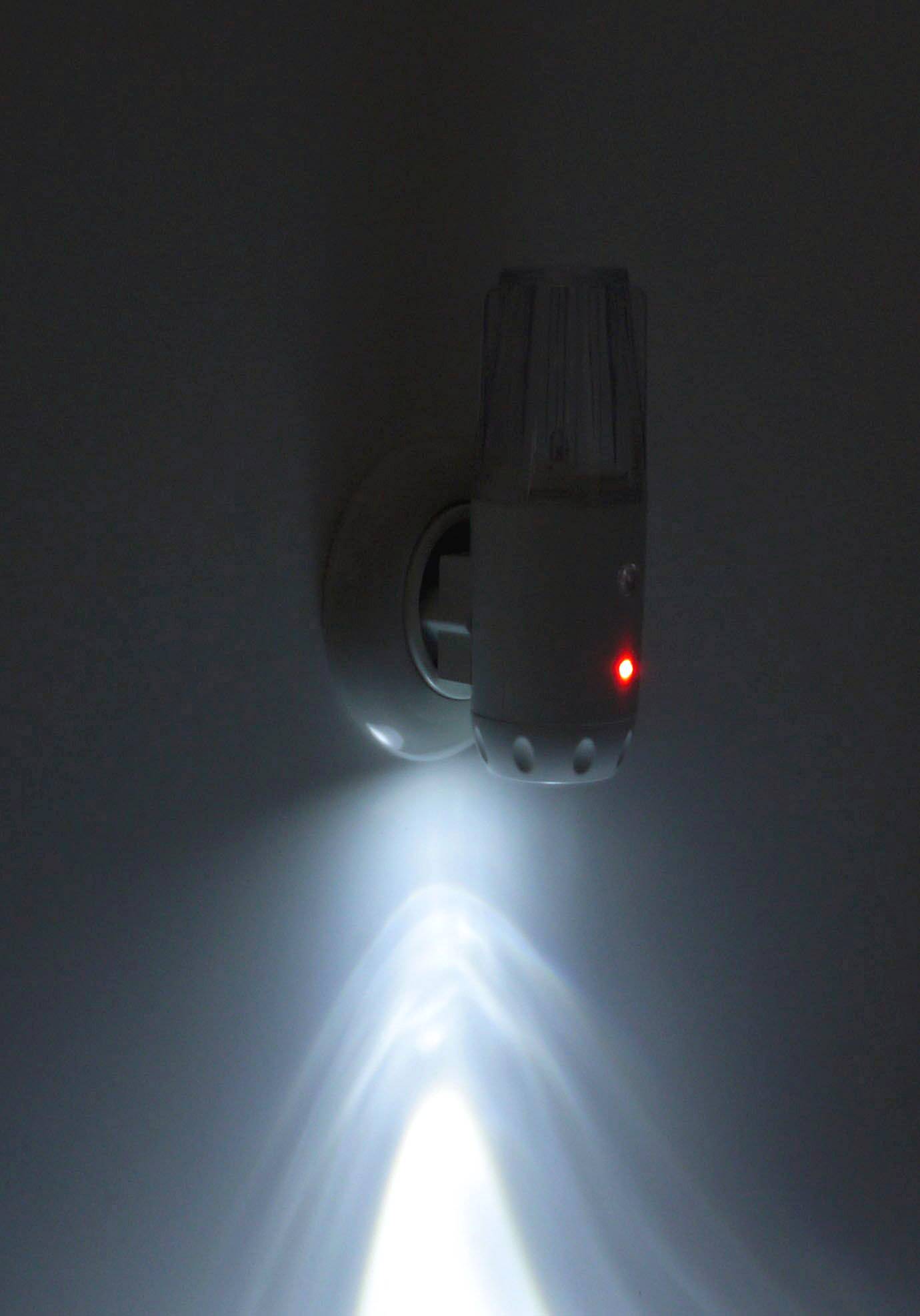 Noční světlo je zastrčeno do elektrické zásuvky. Slabě modře svítí s malým červeným bodem.