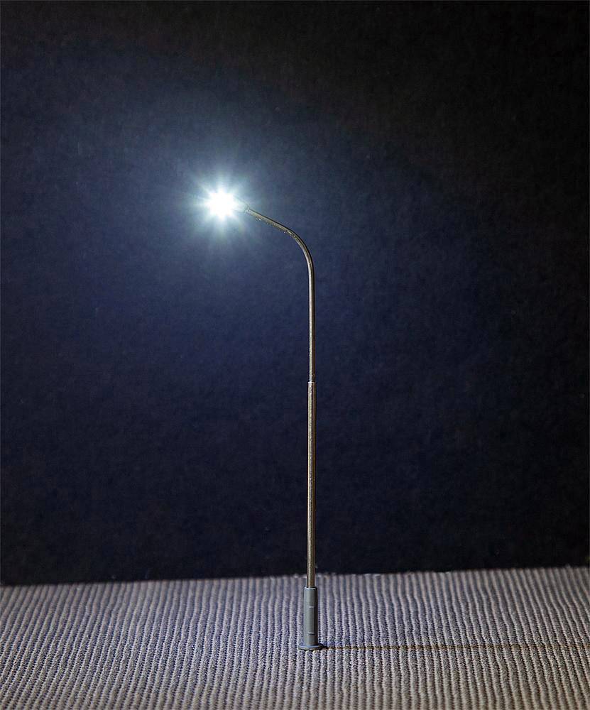 Jedna pouliční lampa jasně svítí v temnotě na strukturovaném povrchu.