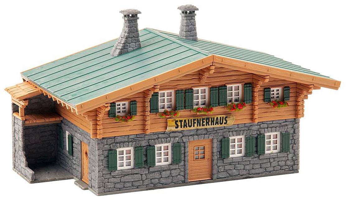 Model tradičního bavorského dřevěného domu se zelenou střechou a nápisem 'Staufnerhaus' nad dveřmi.