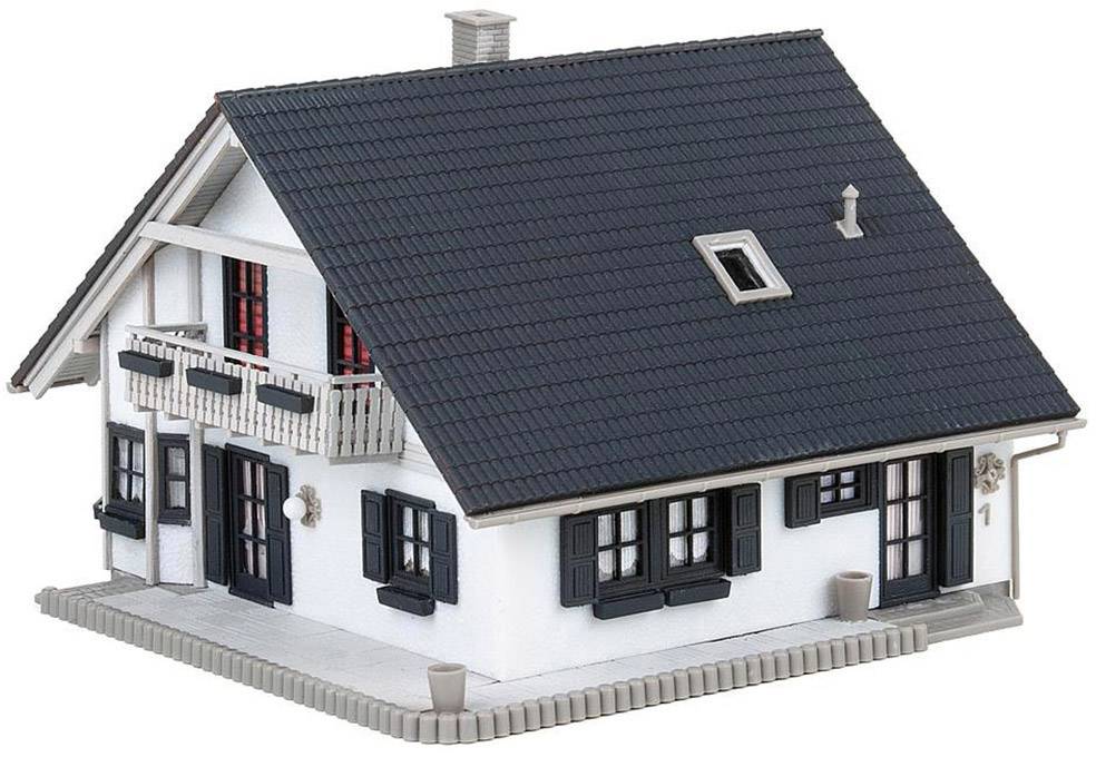 Model dvoupatrového domu s černou střechou, bílou fasádou a balkonem.