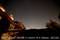Noční obloha nad budovou. Hvězdnatá obloha rozmazaně zachycená na fotografii s textem 'Tracking test: ORION F=16mm f4.0 300sec. ISO100'.