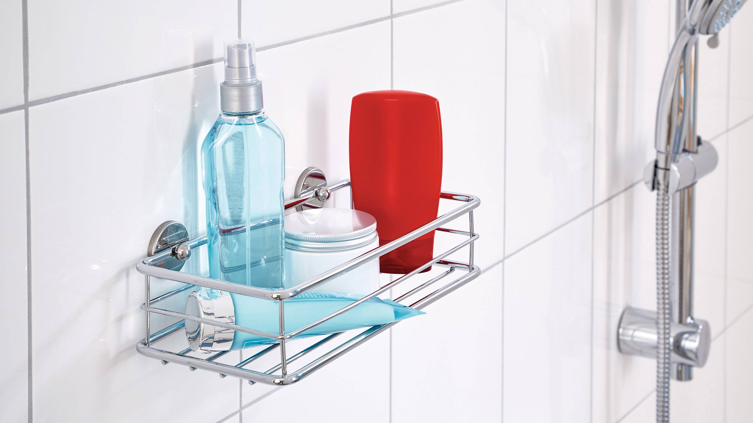 Police ve sprše na stěně s různými kosmetickými produkty: modrá sprejová láhev, červená láhev a malá kulatá nádoba.