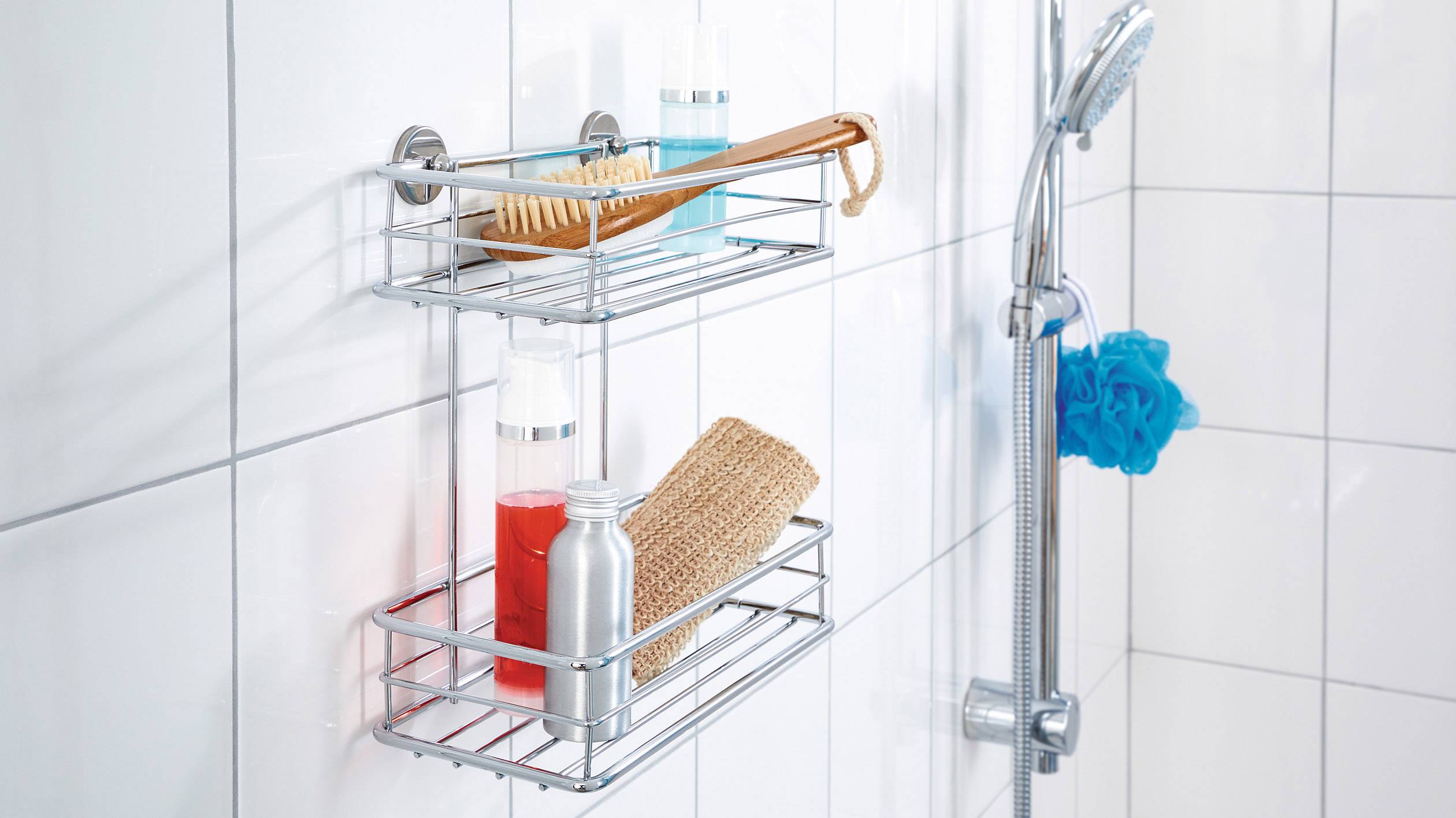 Polička do sprchy s lahvičkami, kartáčem a houbou v obložené koupelně.