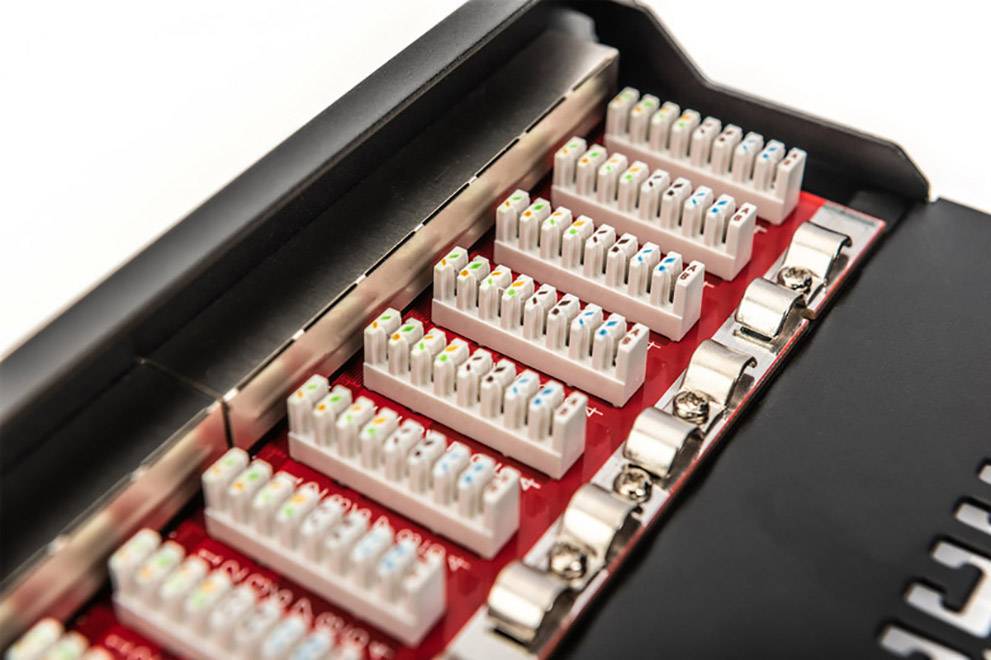 Detailní záběr patch panelu s několika řadami barevných ethernetových konektorů. Používá se v systému síťové distribuce.
