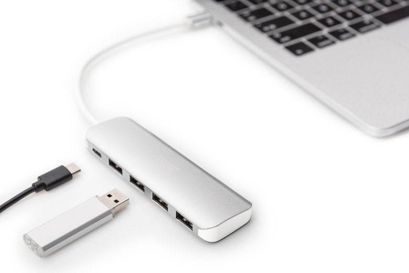 Laptop s připojeným USB hubem, několika USB porty a USB flash diskem vedle na bílém pozadí.