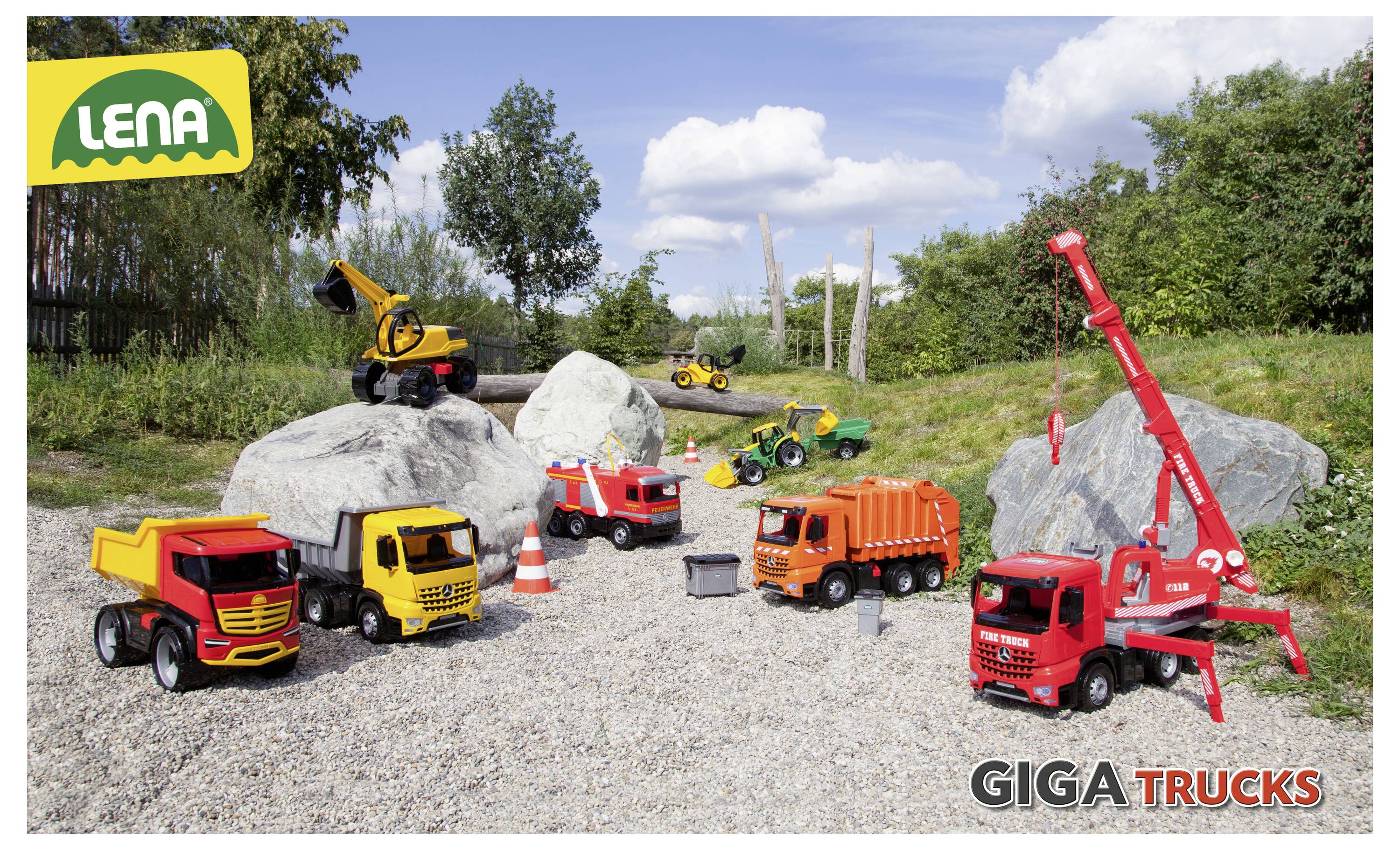 Hračkářské stavební náklaďáky a vozidla jsou rozmístěny na štěrku s kameny a trávou. Viditelné značky: 'Lena' a 'Giga Trucks'.