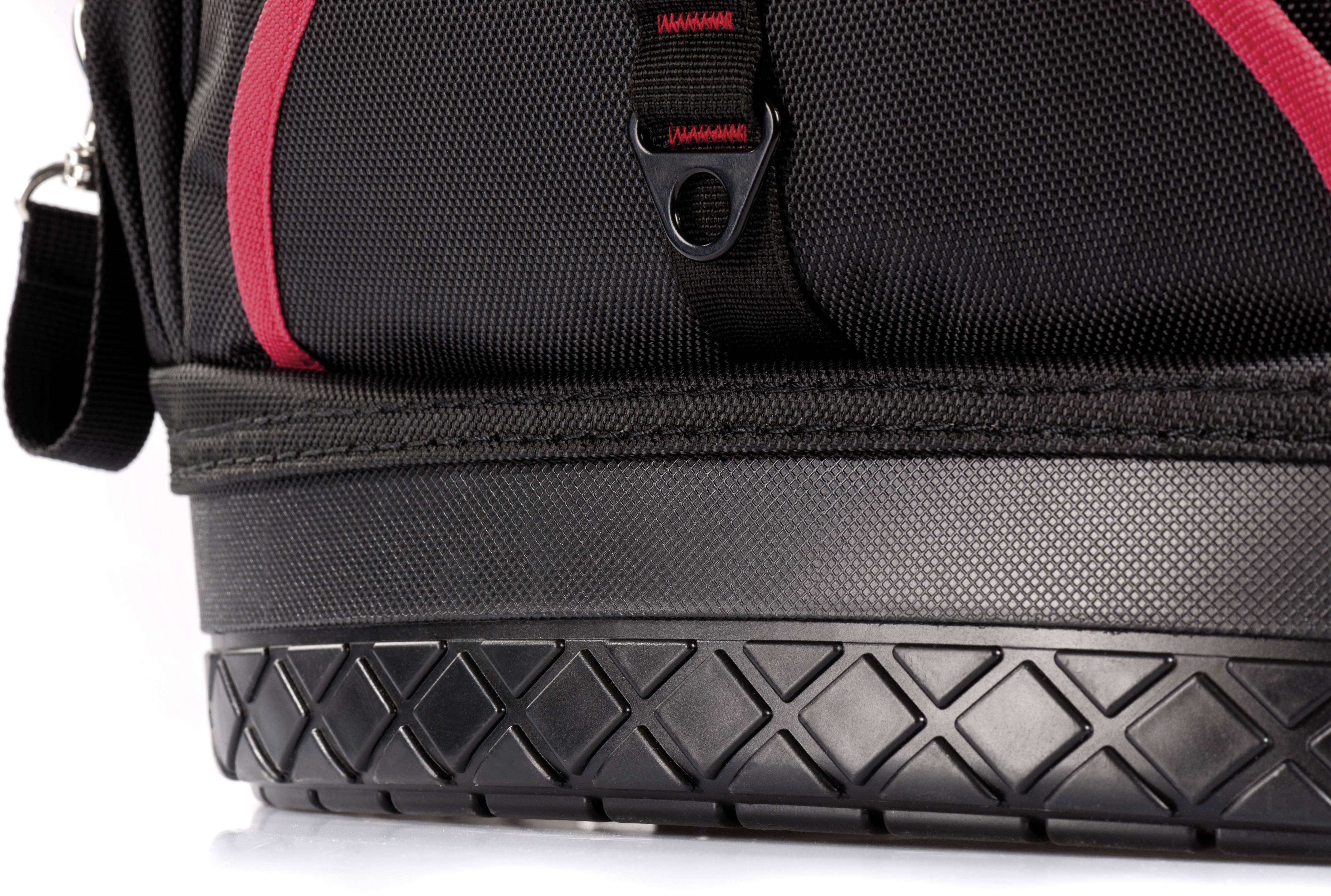 Detailní záběr černého kufru s červeným detailem, robustním dnem a popruhy. Ideální pro cestování nebo přepravu předmětů.