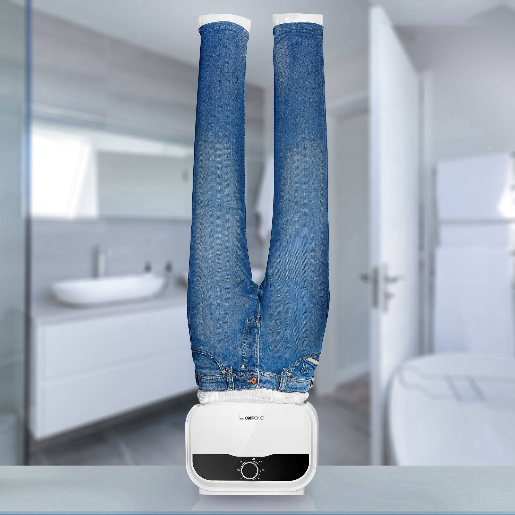 Pračka stojí převrácená vzhůru nohama, přičemž z bubnu trčí modré džínové nohavice. Nachází se v moderní koupelně.