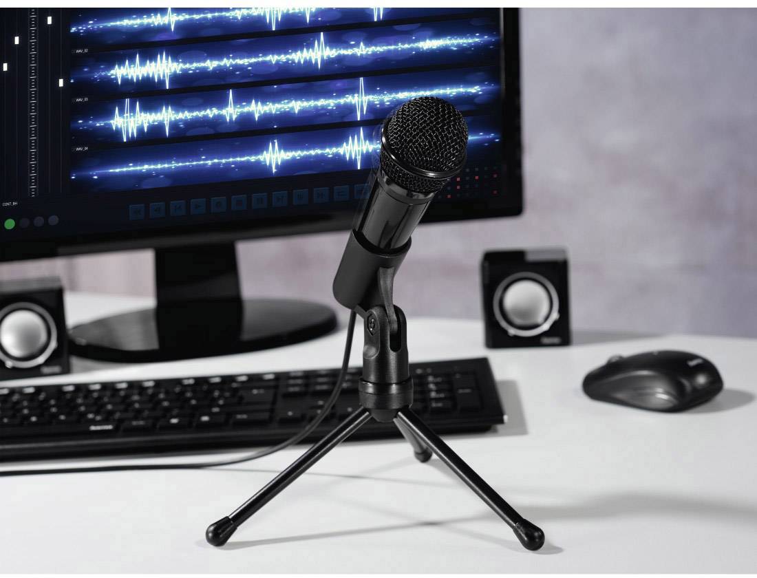Mikrofon před monitorem s audio vlnami a reproduktory; zobrazuje prostředí pro nahrávání nebo úpravu zvuku.
