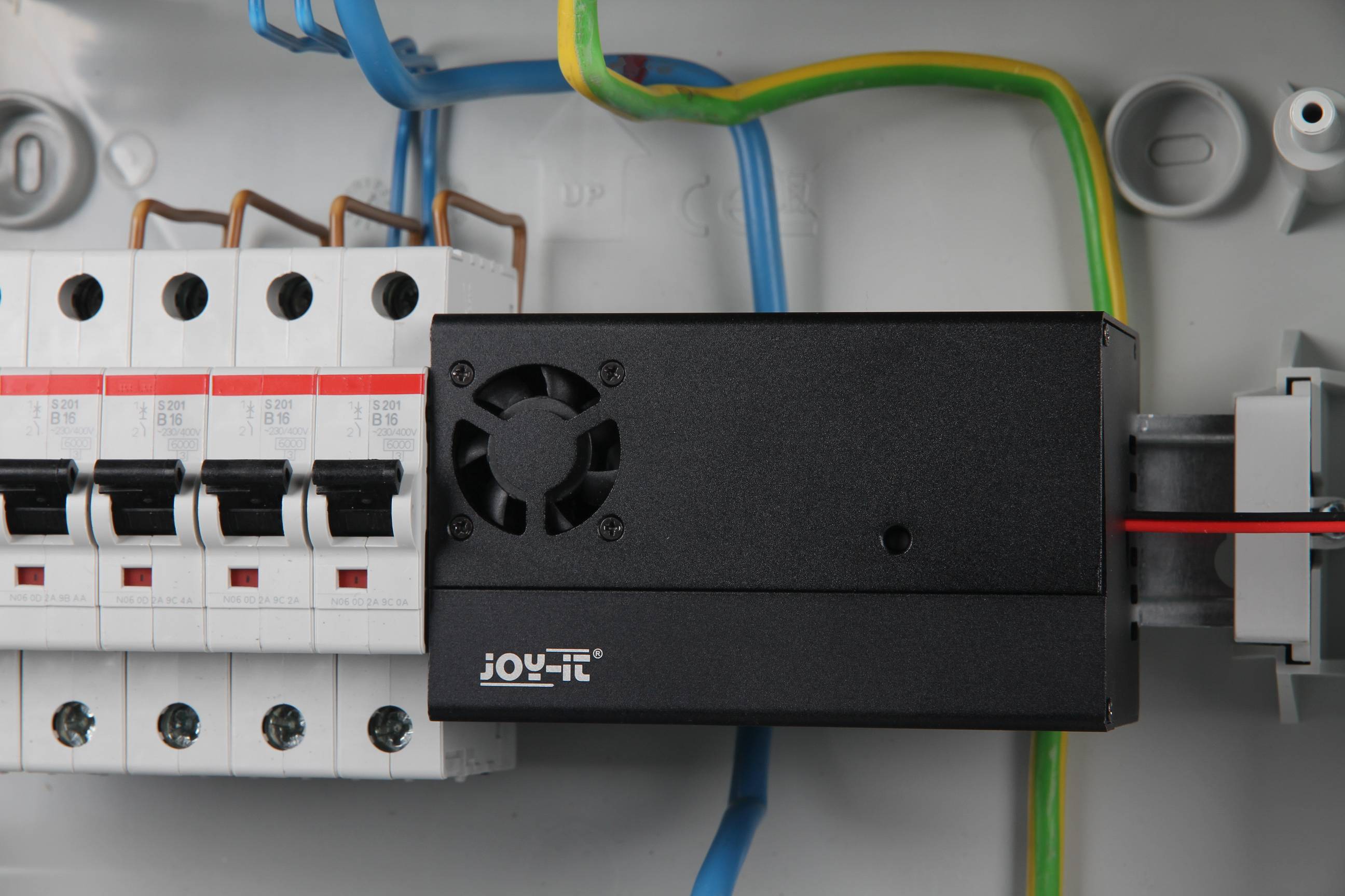 Rozvodná skříň s několika jističi a ventilačním modulem. Barevné kabely propojují jednotlivé komponenty.