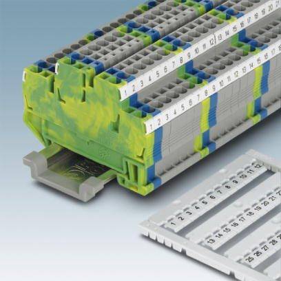 Šedá a zelená svorková jednotka s očíslovanými svorkami, pravděpodobně určená pro elektrické obvody, leží na povrchu.
