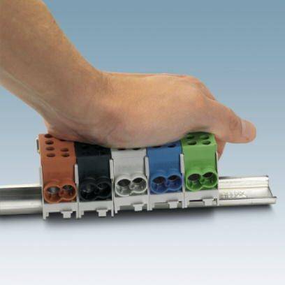 Jedna ruka montuje různobarevné svorky na kovové liště.