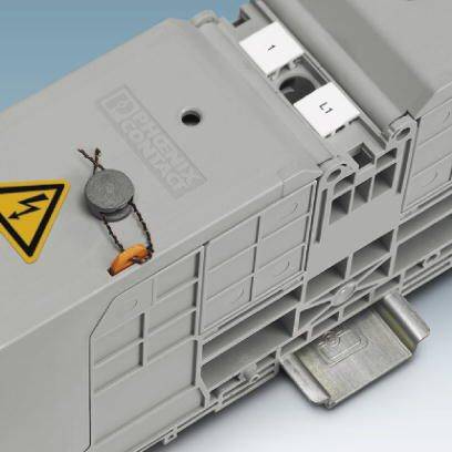 Šedý elektrický spínač s výstražným symbolem vysokého napětí je připevněn na kovovém držáku.