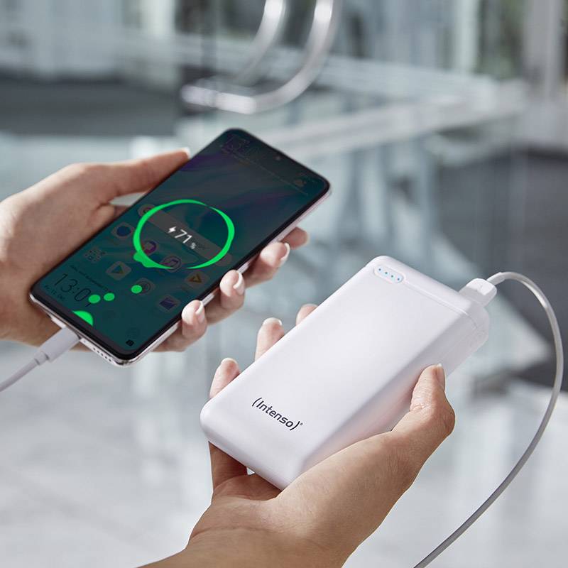 Jedna ruka drží smartphone, který je připojen k powerbance a nabíjí se. Pozadí je rozmazané.